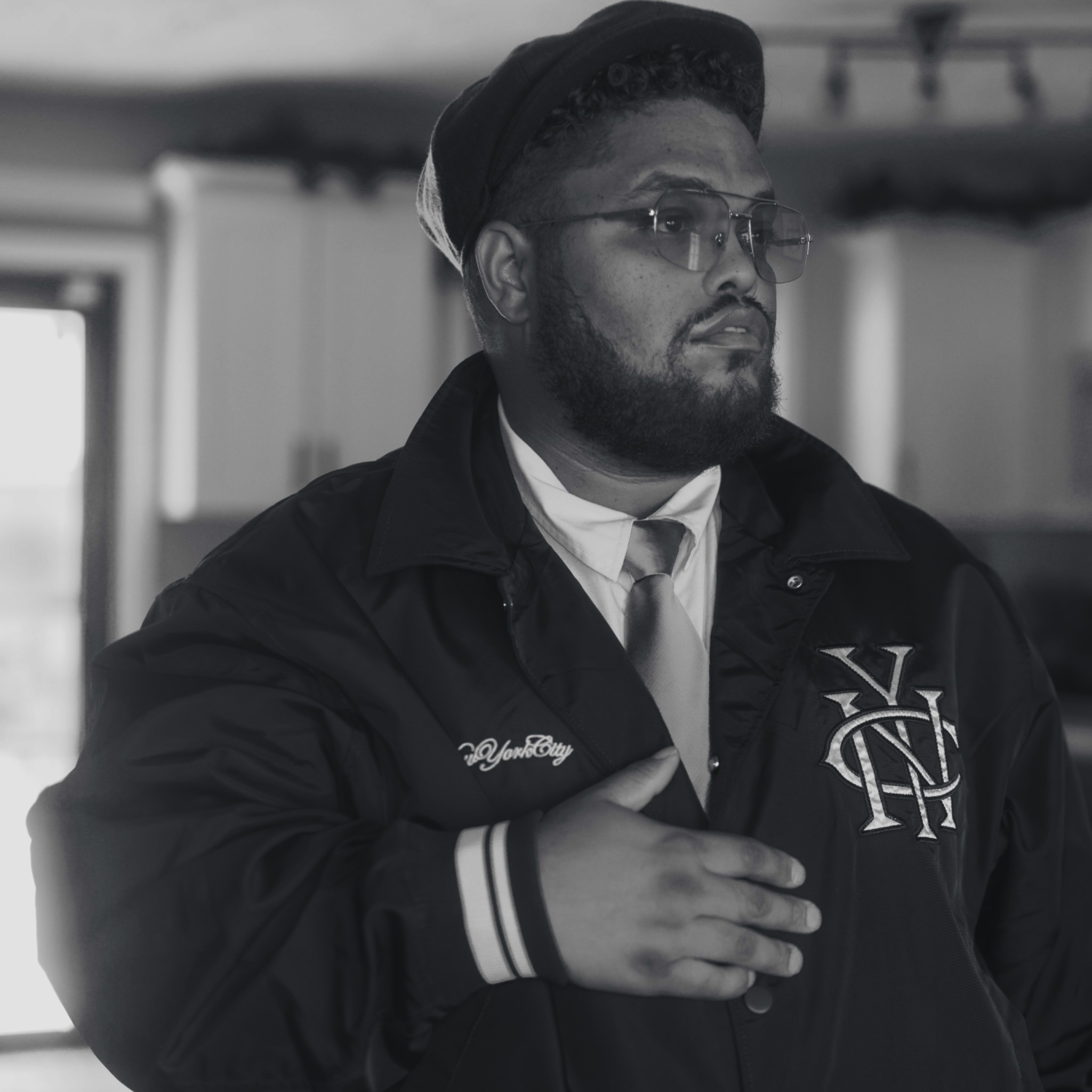 Paul Bill Jr. in a cap and varsity jacket, photographed in black and white